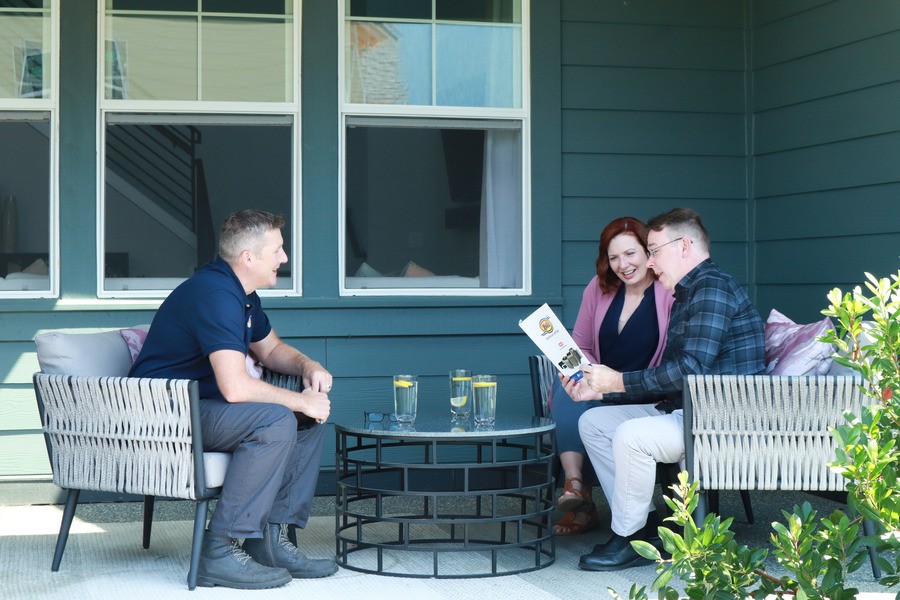 An HVAC contractor speaking to a couple on the porch.